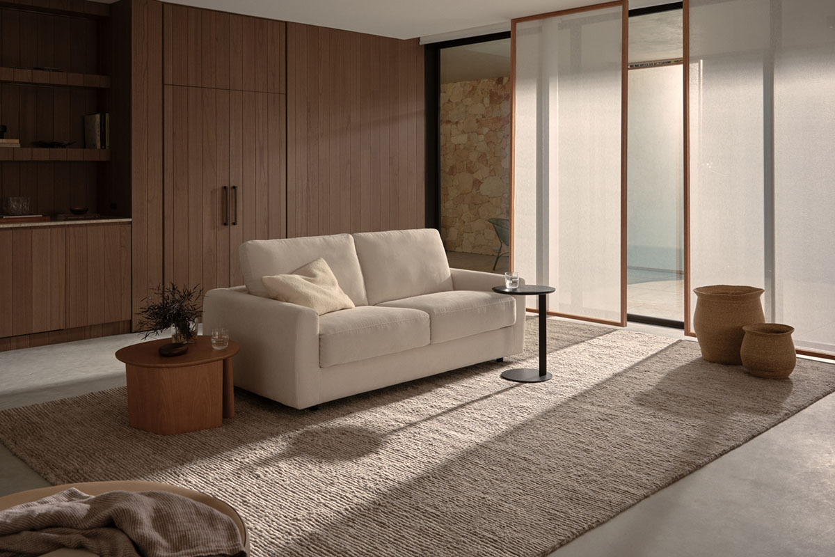 Modern living room with a cream sofa, warm wooden accents, and soft natural light filtering through sheer blinds.